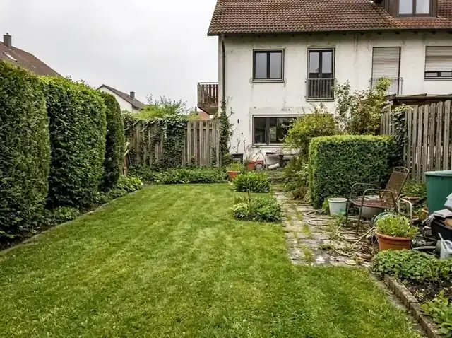Derselbe Garten nach der Pflege mit gemähtem Rasen und freigestellten Beeten