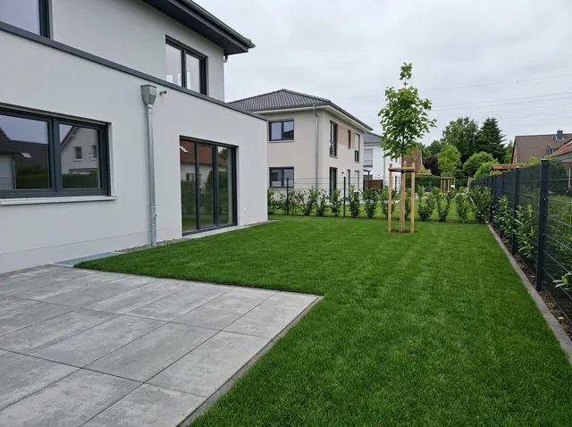 Dieselbe Fläche hinter dem Neubau mit fertigem Rollrasen bis an die Terrassenkante