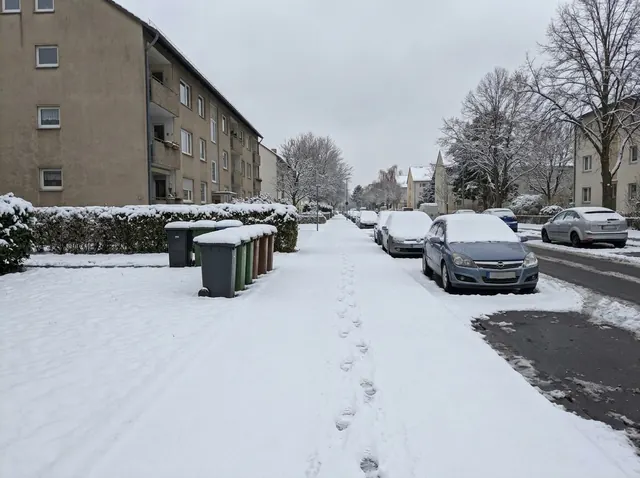 Verschneiter Gehweg vor einem Wohnhaus, unberührte Schneedecke