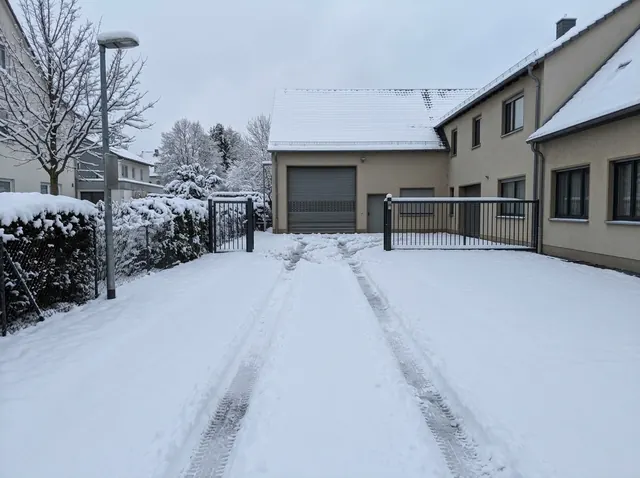 Zugeschneite Hofeinfahrt mit tiefen Fahrspuren im Schnee